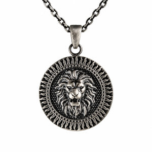 A silver-toned round pendant necklace featuring a detailed lion head design in the center, suspended from a matching chain against a plain white background.