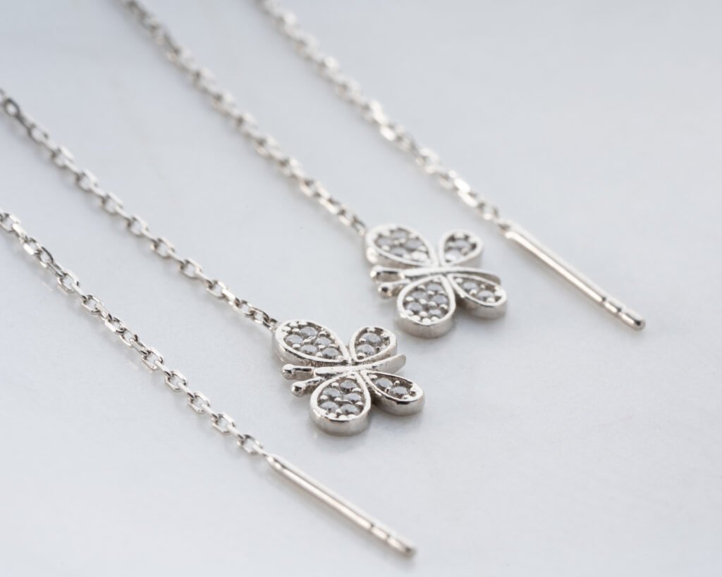 silver clover threader earrings displayed on a white dish