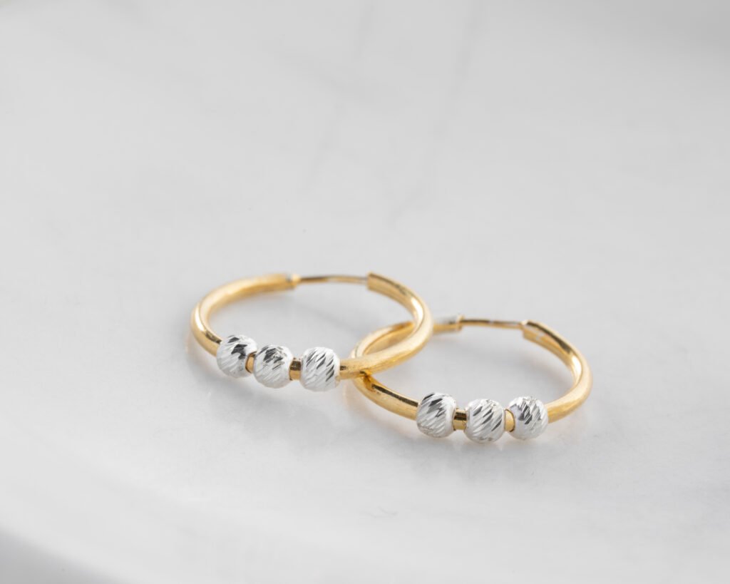 gold-plated hoop earrings with textured silver beads on white background