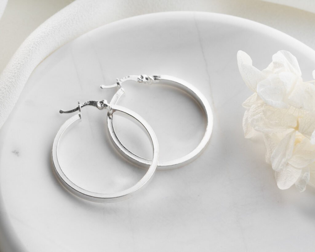 Polished sterling silver hoop earrings on white background
