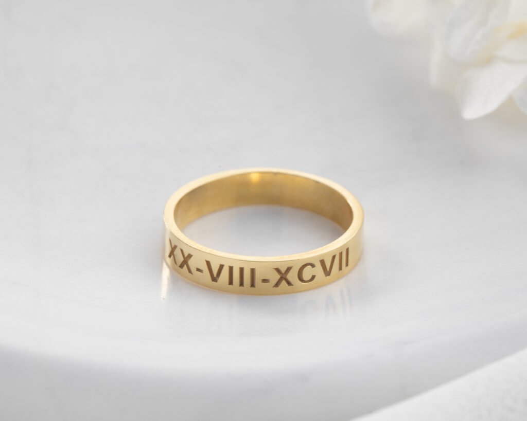 gold Roman numeral band ring on soft textured background