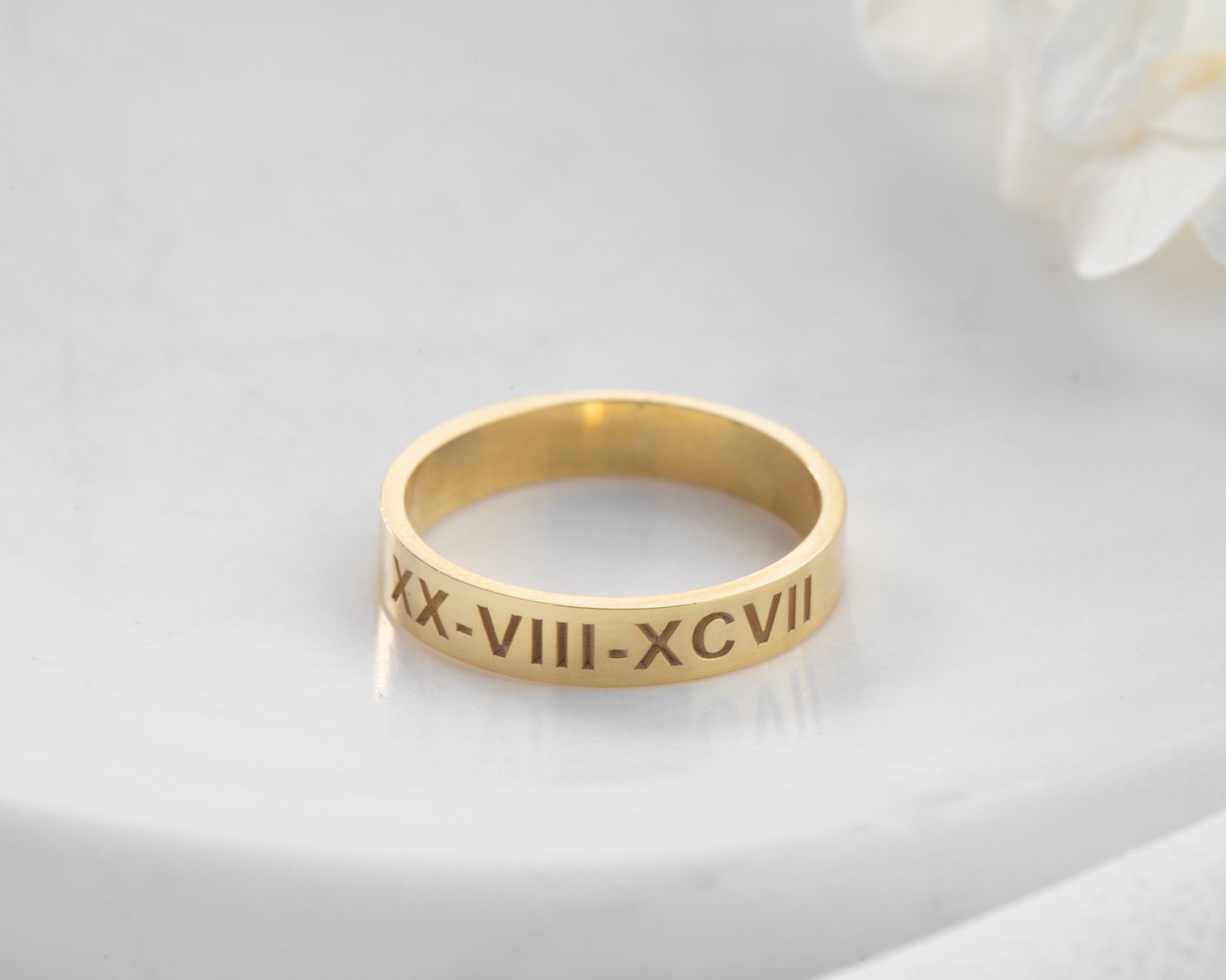 gold Roman numeral band ring on soft textured background