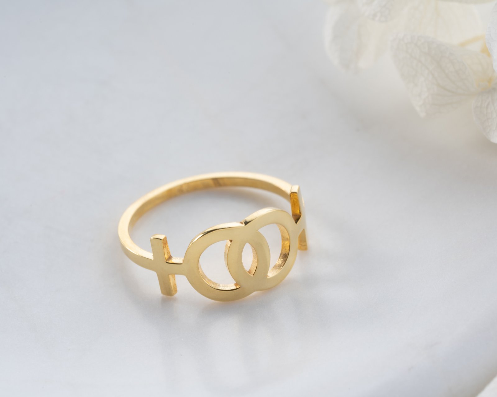 gold interlocking gender symbols ring on light background