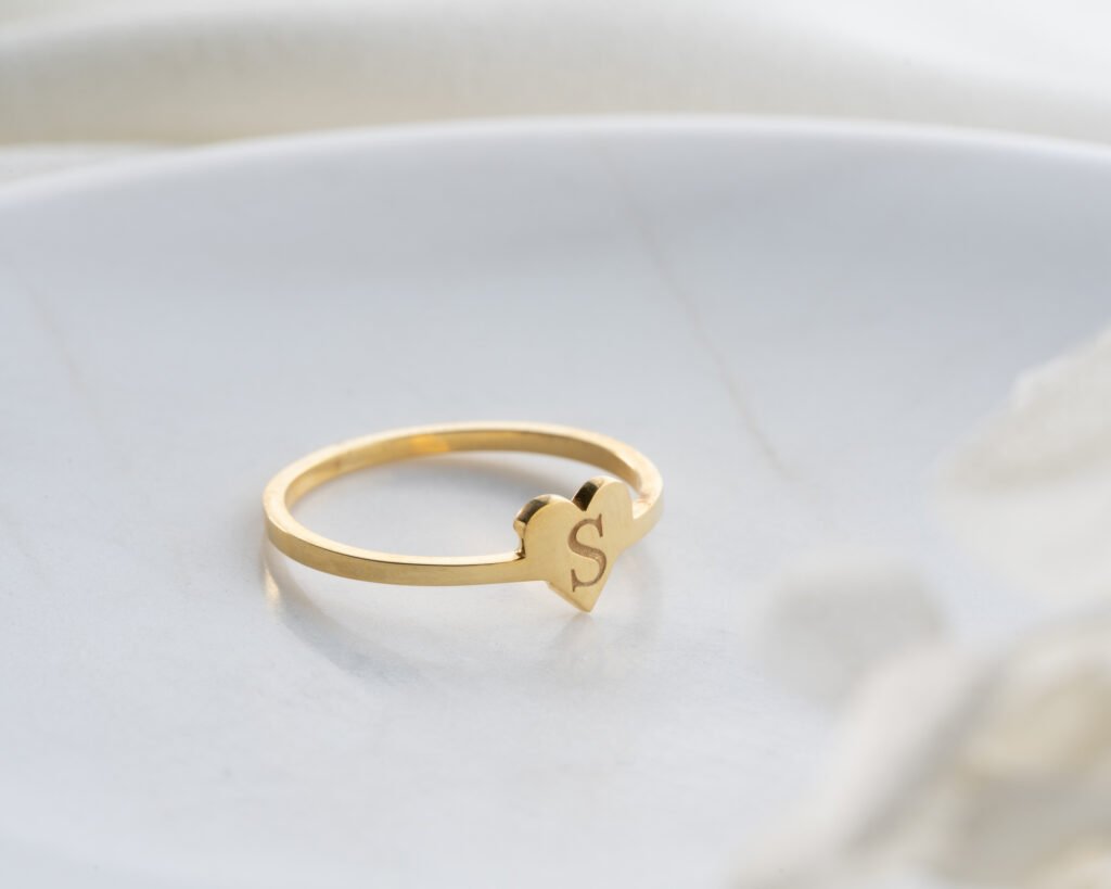 gold heart initial ring on soft white background