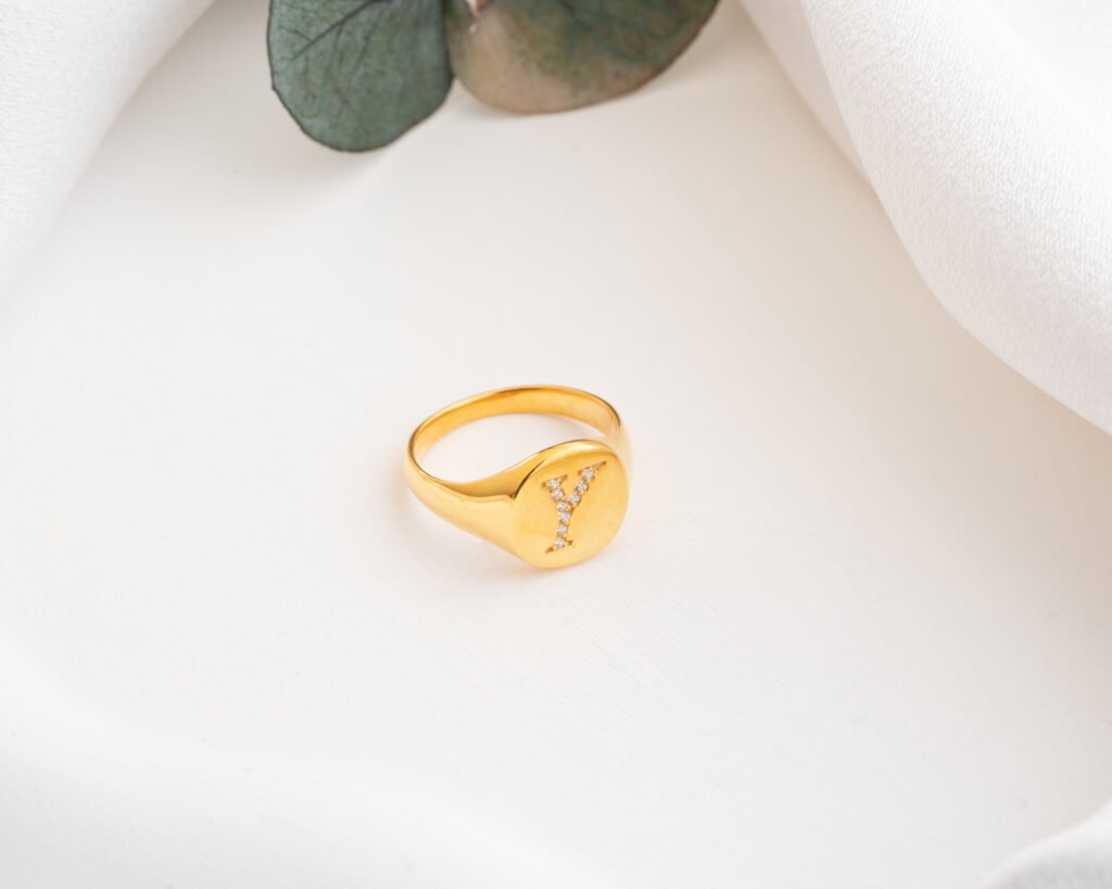 CZ initial signet rings in gold, silver, and rose gold on white background