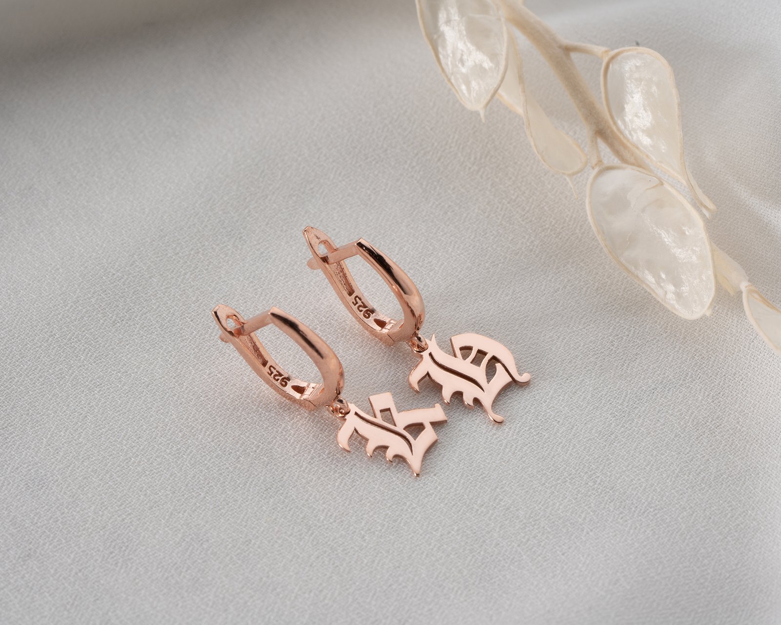 rose gold monogram drop earrings on textured background