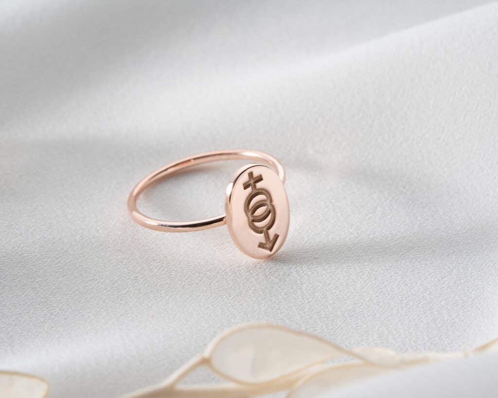 rose gold inclusive symbol signet ring on soft light background