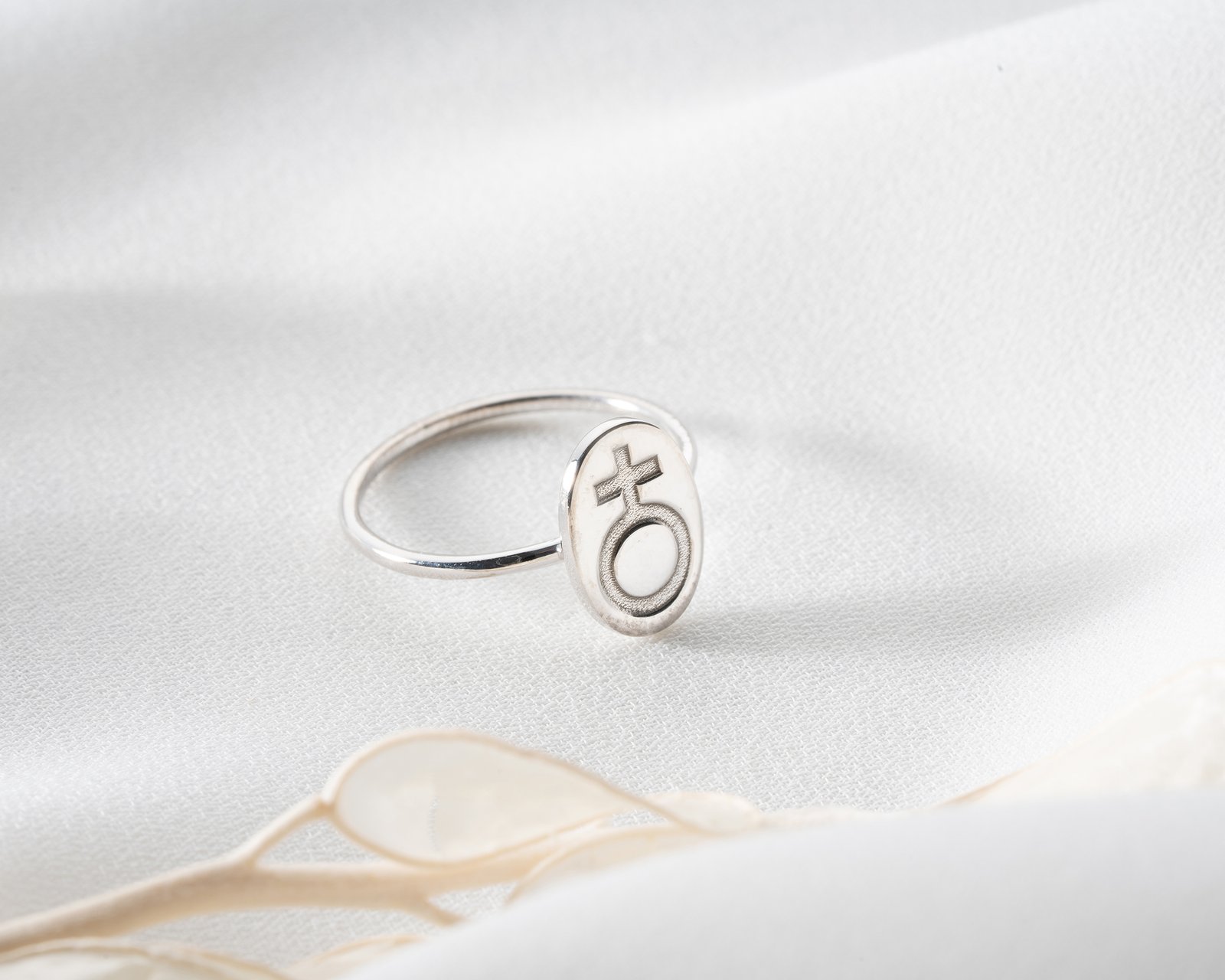 silver female symbol signet ring on soft textured background