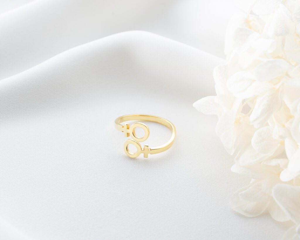 gold double female symbol ring on textured background